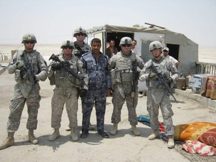 American soldiers standing with an Iraqi police officer at a checkpoint