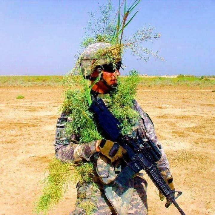 A U.S. soldier in camouflage and natural concealment during a mission in Iraq